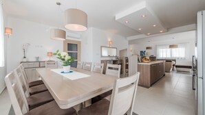 A modern kitchen with a central island, a dining area with a large table and chairs, and a living space with a sofa and a TV. - Dalmacija Viii in Suko an (Sukosan)
