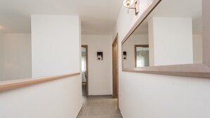 A narrow hallway with a wooden handrail on the left, a tiled floor, and a large mirror on the right. - Dalmacija Viii in Suko an (Sukosan)