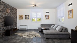 A modern living room with a grey sofa, a flat-screen TV, a fireplace, and artwork on the walls. - Dolce Bacio in Kavran (Marcana)