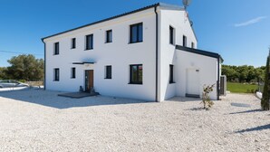 A modern two-story house with a gravel driveway, a satellite dish, and a small garden area. - Dolce Bacio in Kavran (Marcana)