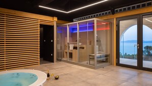 A modern spa area with a hot tub, glass-enclosed shower, and a view of the sea. - Complex Wind Rose in Maru i i (Omis)