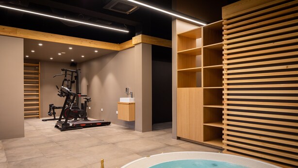 A modern spa area with a hot tub, exercise equipment, and wooden shelving. - Complex Wind Rose in Maru i i (Omis)