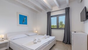 Une chambre d’hôtel avec un grand lit, deux tables de chevet, une télévision et une fenêtre avec des rideaux.