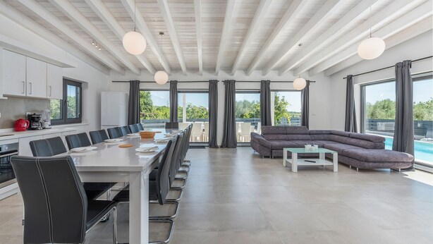 Une cuisine moderne avec un coin repas, une grande fenêtre et une vue sur la piscine.