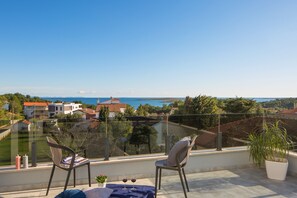 A balcony with two chairs, a table with a blue cloth, and a potted plant. - K in Premantura With 4 Bedrooms and 4 Bathrooms (Medulin)