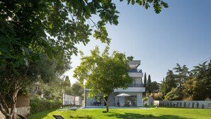 Une maison moderne dotée d’une piscine, d’une pelouse et de deux chaises longues.