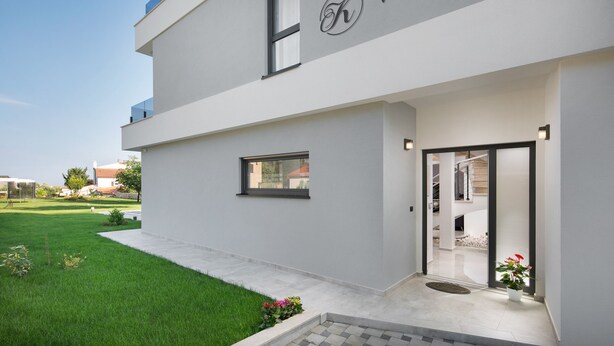 Une villa moderne dotée d’un toit plat, d’une grande entrée et d’une pelouse bien entretenue.
