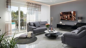 Un salon moderne avec un canapé gris, une table basse et un téléviseur fixé au mur.