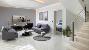 Un salon moderne avec un canapé gris, une table basse et un escalier menant à une autre pièce.