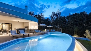 A modern outdoor swimming pool with lounge chairs and umbrellas, surrounded by a deck and trees. - Viktor in Kr an With 7 Bedrooms and 7 Bathrooms (Krsan)