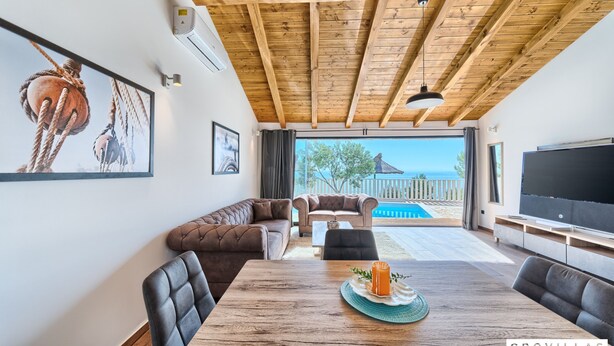 A spacious living area with a wooden ceiling, a large TV, and a view of the sea. - Filip in Murter With 4 Bedrooms and 2 Bathrooms (Tisno)