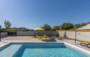 A swimming pool with clear blue water, surrounded by lounge chairs and a yellow umbrella. - Elite 1 in Pula With 4 Bedrooms and 4 Bathrooms (Pula)