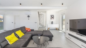 A modern living room with a grey sectional sofa, a black coffee table, and a flat-screen TV. - Elite 1 in Pula With 4 Bedrooms and 4 Bathrooms (Pula)