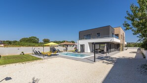 A modern two-story house with a swimming pool, outdoor seating, and a well-maintained lawn. - Elite 1 in Pula With 4 Bedrooms and 4 Bathrooms (Pula)
