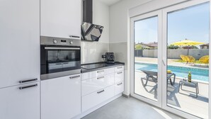 A modern kitchen with white cabinets, a built-in oven, and a coffee maker. - Elite 1 in Pula With 4 Bedrooms and 4 Bathrooms (Pula)