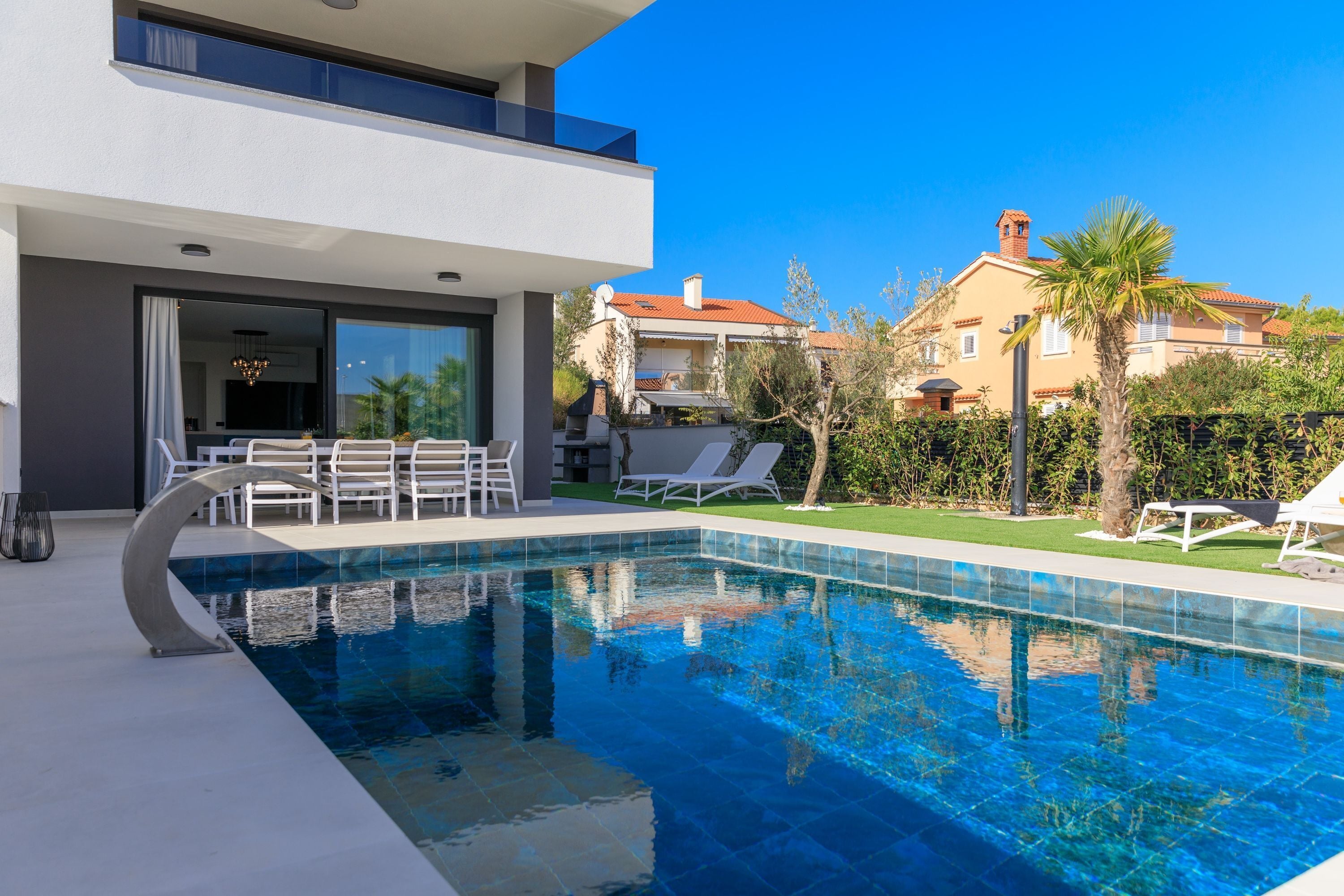 A modern pool area with lounge chairs and a dining area.