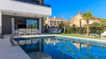 A modern pool area with lounge chairs and a dining area.