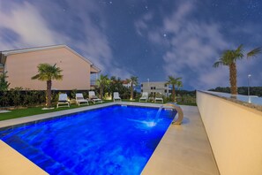 A swimming pool with lounge chairs, palm trees, and a building in the background under a starry night sky. - Lea Magdalena IV in Krk (Krk)