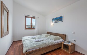 A bedroom with a wooden bed, a nightstand, a window with curtains, and a wall-mounted light fixture. - Undina in Premantura (Medulin)