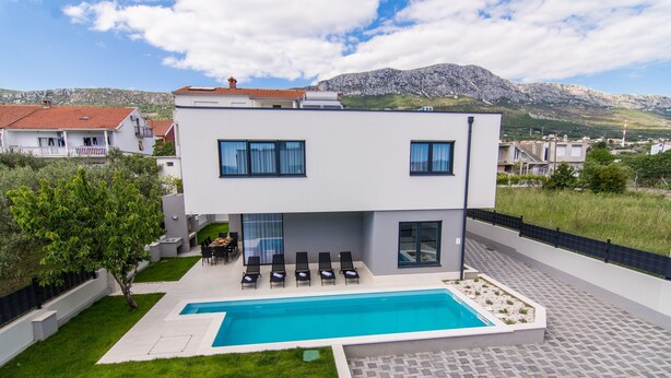 A modern two-story house with a swimming pool, outdoor seating, and a view of the surrounding landscape. - Kastel One in K Kambelovac (Kastela)