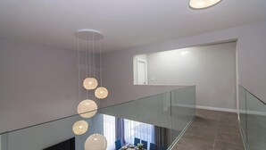 A modern interior with a glass railing, a staircase, and pendant lighting. - Kastel One in K Kambelovac (Kastela)