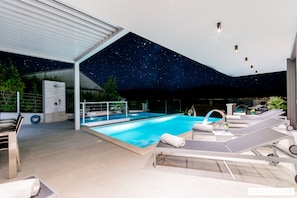 A modern indoor pool area with a starry ceiling, lounge chairs, and a clear view of the pool. - Vitae in Sutivan With 3 Bedrooms and 3 Bathrooms (Sutivan)