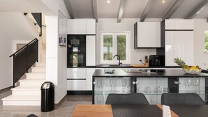 Een moderne keuken met witte kasten, een zwart aanrecht en een glazen eettafel.