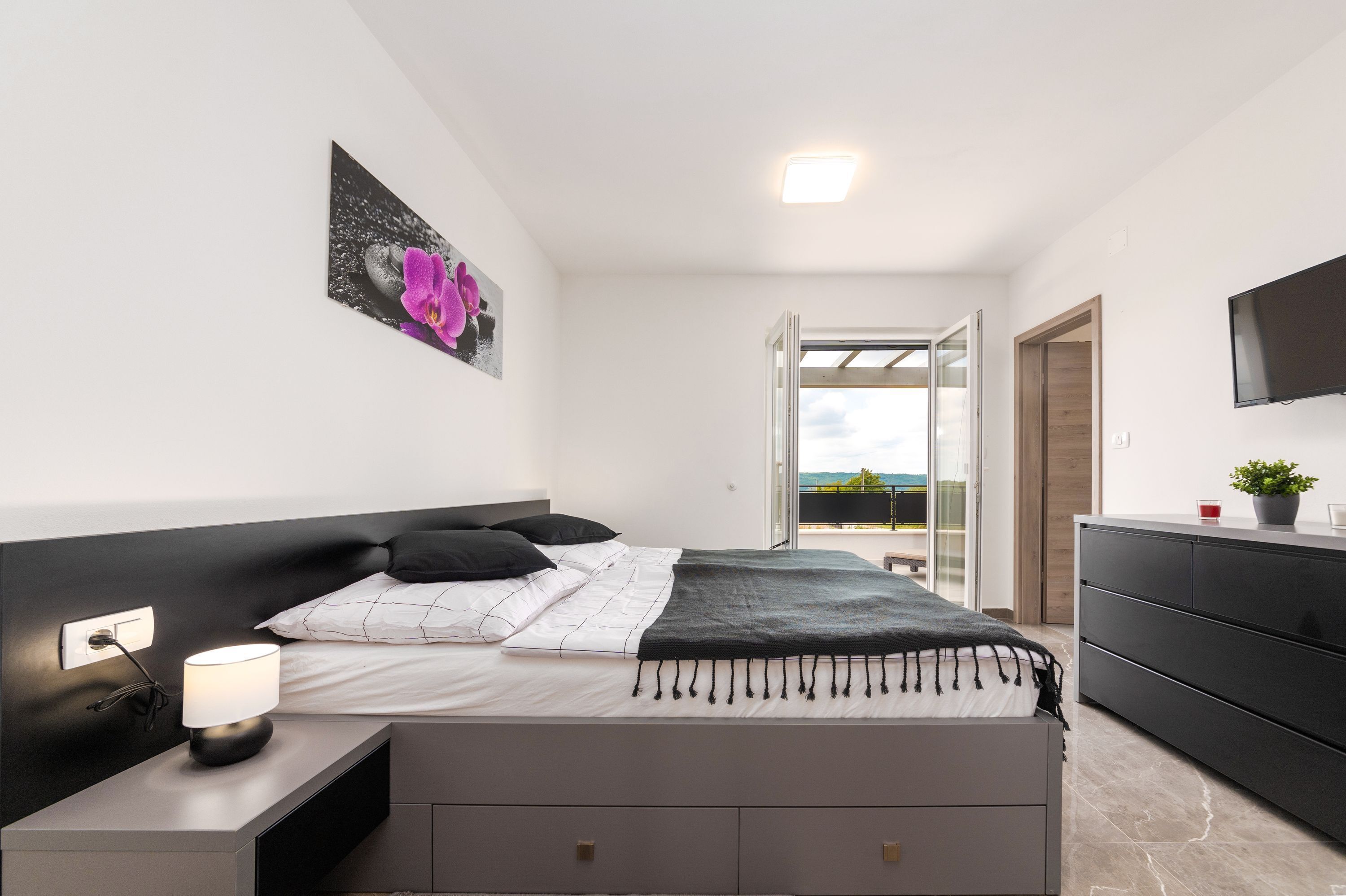 A modern bedroom with a bed, bedside table, and a TV.