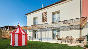 A two-story house with a covered patio area and a red and white striped tent in the yard. - Mediterranea in Umag (Umag)