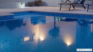 Ein Poolbereich mit Liegestuhl, einer Sitzecke und einem kleinen Tisch.