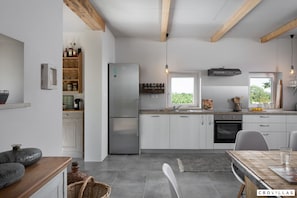 Een moderne keuken met witte kastjes, een roestvrijstalen koelkast en een houten plafond.