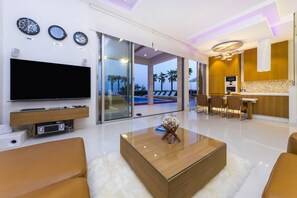 A modern living room with a flat-screen TV, a wooden coffee table, and a large glass door leading to a pool area. - Petra-pag in Novalja (Novalja)