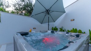 A hot tub with a large umbrella, surrounded by plants and a white wall. - Lorena Crikvenica in Crikvenica (Crikvenica)