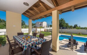 Un patio exterior con piscina, mesa de comedor y sillas.