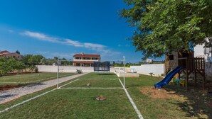 A grassy outdoor area with a basketball court, a slide, and a wooden play structure. - Dija in Jur i i With 3 Bedrooms and 3 Bathrooms (Svetvincenat)