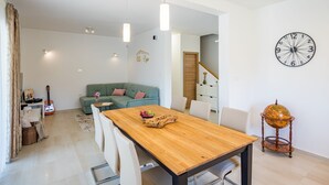 A modern living room with a wooden dining table, white chairs, a green sofa, and a globe on a stand. - Dija in Jur i i With 3 Bedrooms and 3 Bathrooms (Svetvincenat)