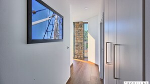 A hallway with a framed picture of a ship's rigging, a stone wall, and a door leading to a room with a modern design. - Vita in Muter With 6 Bedrooms and 6 Bathrooms (Tisno)