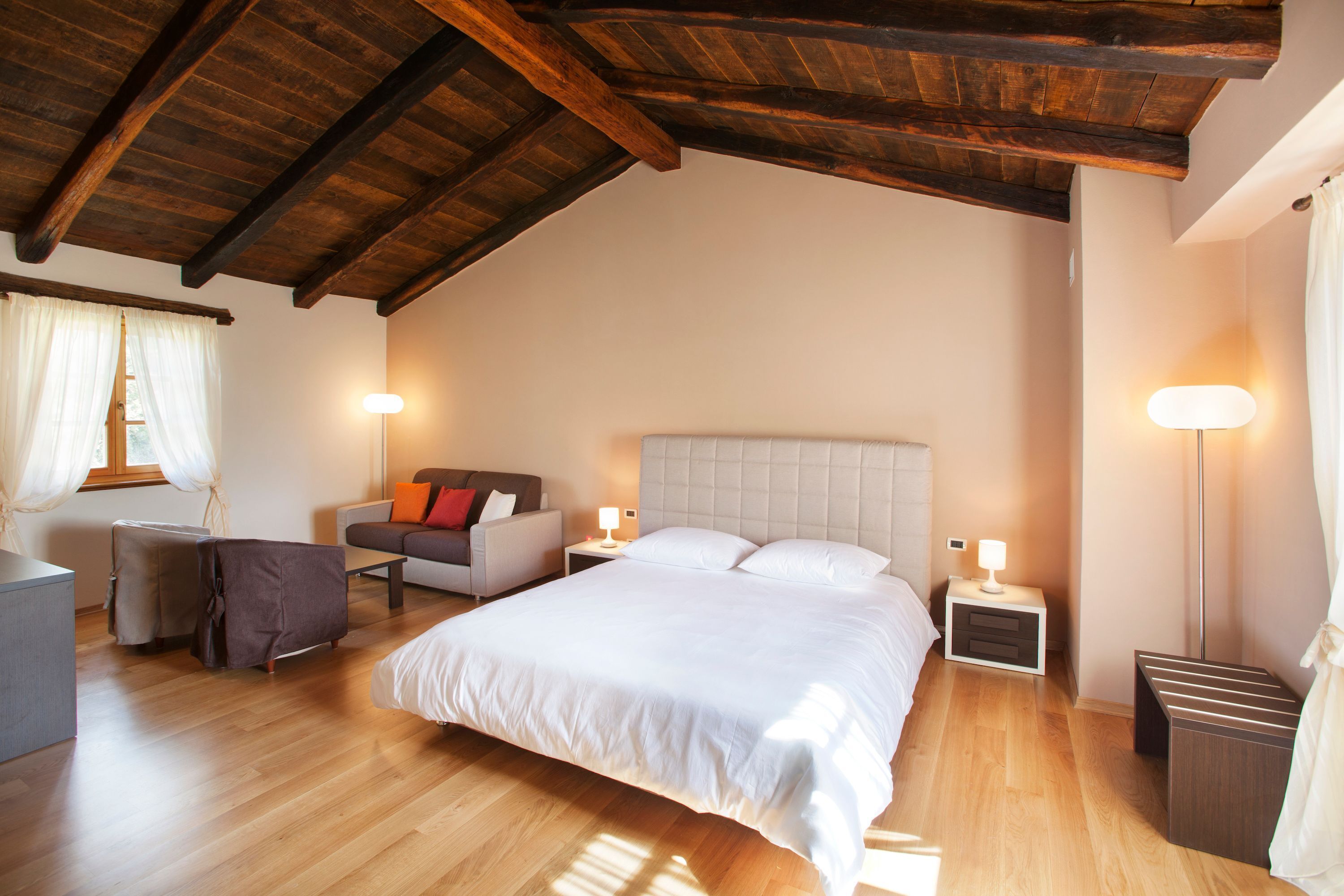 A bedroom with a large bed, a nightstand, a chair, and a lamp.