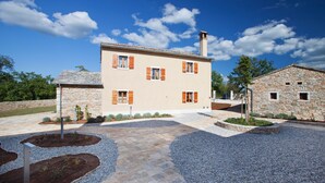 A two-story house with a stone facade, multiple windows with shutters, and a paved courtyard with gravel and stone pathways. - Poropati in Groznjan (Groznjan)