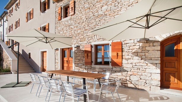 A stone building with a wooden table and chairs outside, a staircase, and a door. - Poropati in Groznjan (Groznjan)