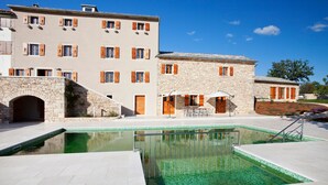 A pool area with stone buildings, a stone archway, and a clear blue sky. - Poropati in Groznjan (Groznjan)