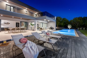 Una casa moderna con piscina, mobiliario exterior y zona de comedor.