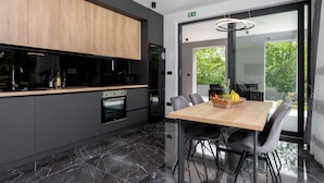 A modern kitchen with dark cabinetry, a wooden countertop, and a marble floor. - Alison Deluxe in Zupanici (Sveta Nedelja)