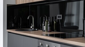 A modern kitchen with a black countertop, stainless steel appliances, and wine bottles. - Alison Deluxe in Zupanici (Sveta Nedelja)