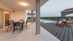 A covered outdoor area with a pool, seating, and a table. - Dalmacija VI in Suko an (Sukosan)