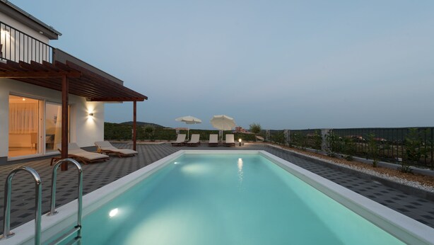 A swimming pool with lounge chairs and umbrellas, surrounded by a landscaped area and a building with a pergola. - Dalmacija VI in Suko an (Sukosan)