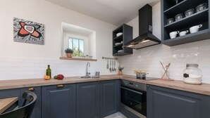 A modern kitchen with dark blue cabinets, a wooden countertop, and a black range hood. - Flego in Motovun With 2 Bedrooms and 1 Bathrooms (Motovun)