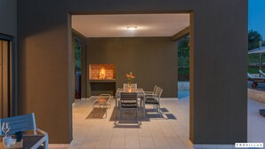 Een buitenterras met een tafel, stoelen, een vuurplaats en uitzicht op de omgeving.