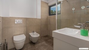 Een moderne badkamer met toilet, hygiëneschuimer en wastafel.