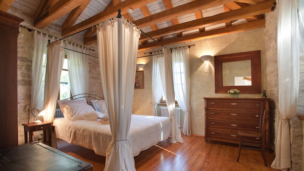 A bedroom with a four-poster bed, wooden floor, stone walls, a dresser, and a mirror. - Gelci in Trget With 3 Bedrooms and 3 Bathrooms (Rasa)